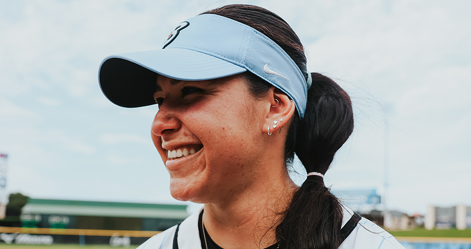 Cori McMillan smiles in her blue Bandits visor with her hair in a bubble braid.